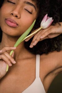 Calm young lady touching flower gently with closed eyes smell good