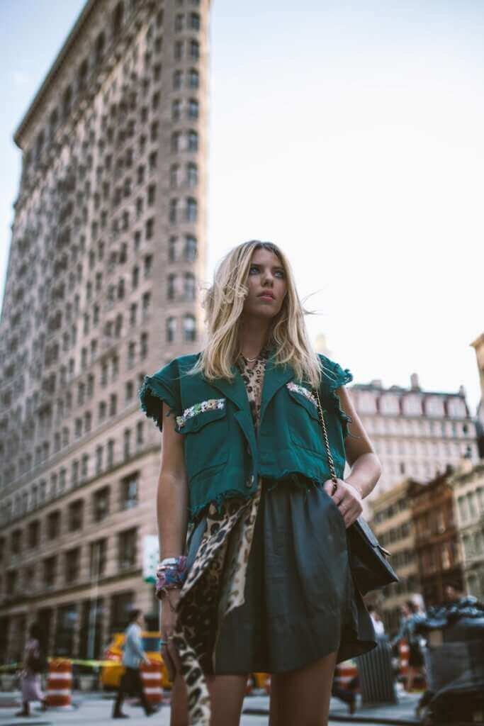 woman wearing green top standing near Flatiron building styling her signature look